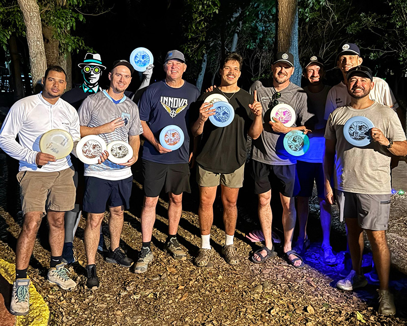 A group of players throwing glowing discs during the first ever glow disc golf round played in the Dominican Republic at Parque Central de Santiago.
