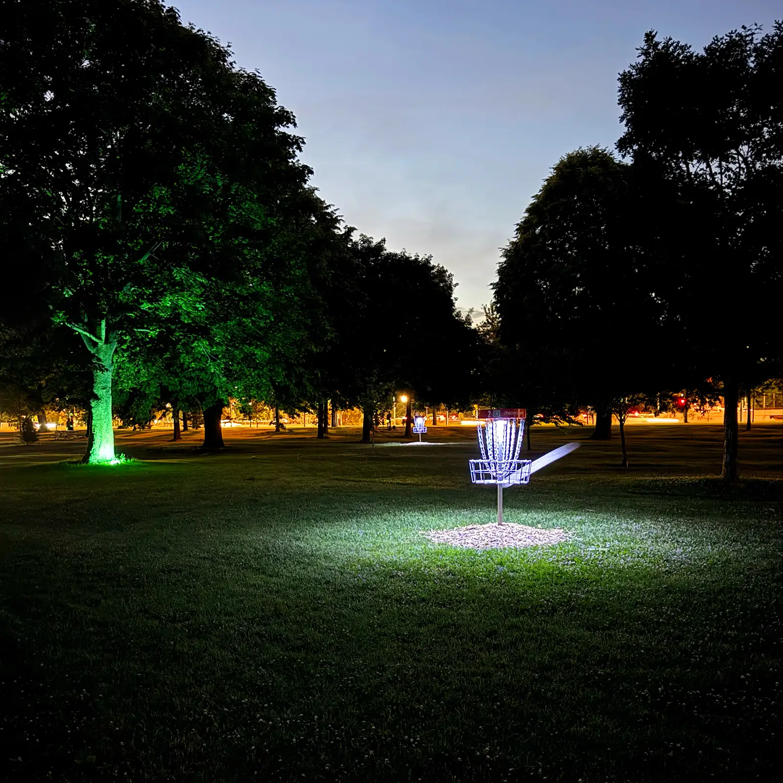 UFO UV basket light attached to disc golf basket, glowing at night