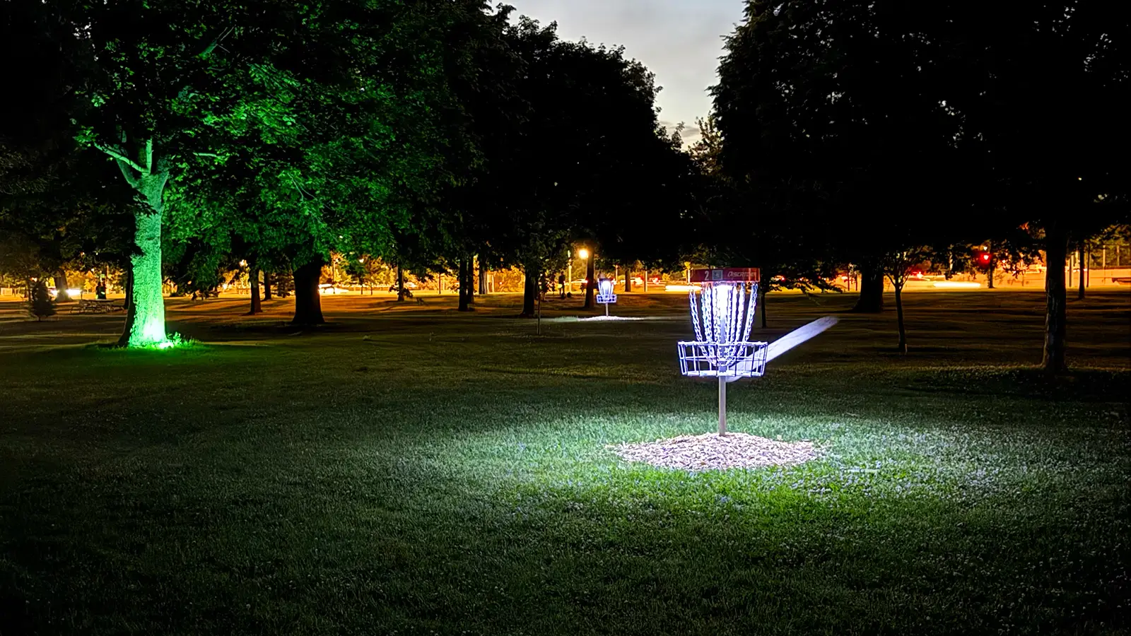 UFO UV basket light attached to disc golf basket, glowing at night