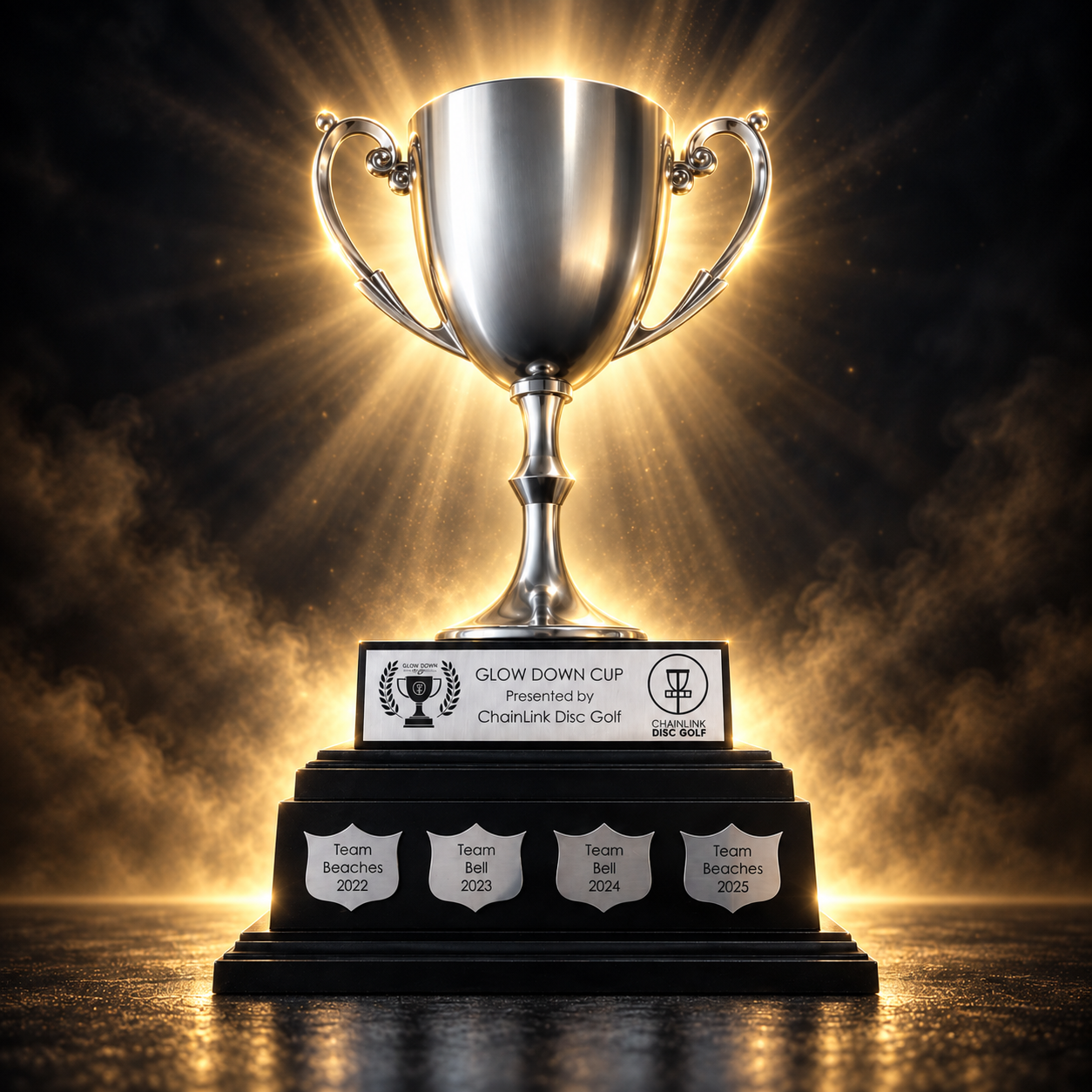 The Glow Down Cup trophy, a silver two-handled cup on a black tiered base, engraved with the winning teams of Toronto's glow disc golf rivalry