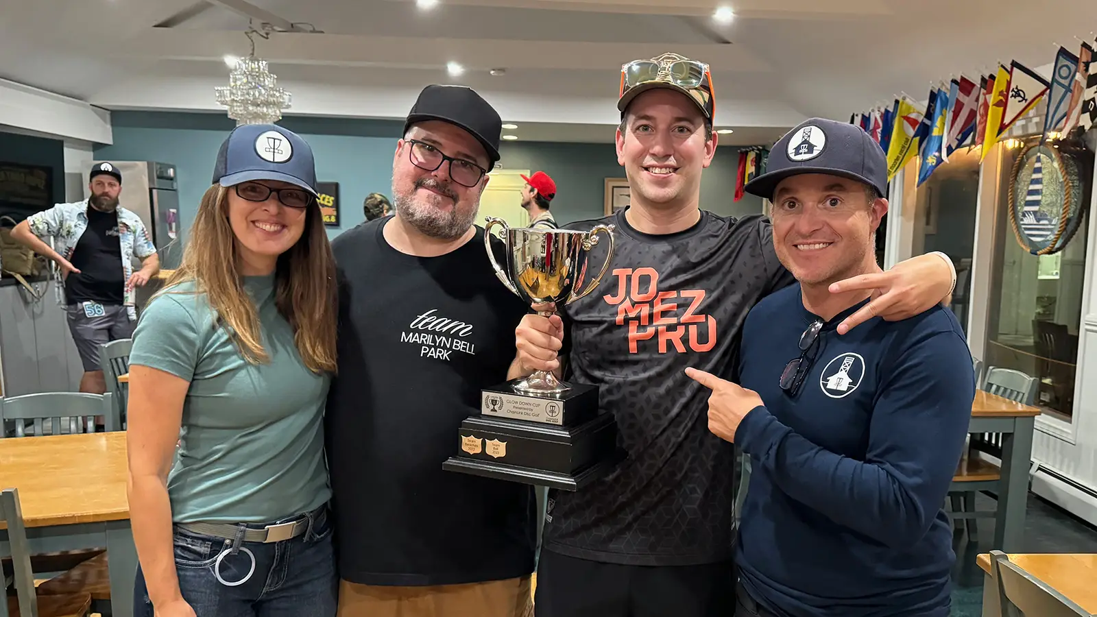Four Glow Down Cup organizers and players posing together with the trophy