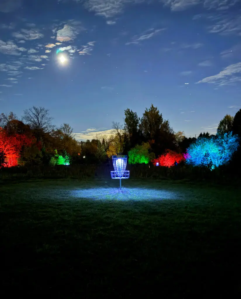 A glowing keg in the foreground with a rainbow of lit trees and a basket in the distance at GLOWLOT