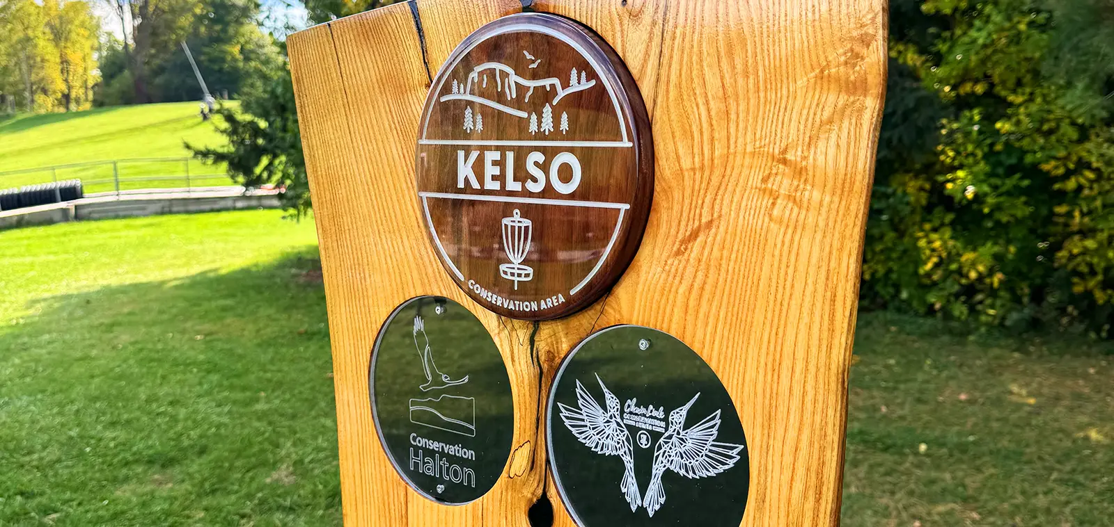 Wooden course sign at Kelso with the Kelso Conservation Area, Conservation Halton, and ChainLink Conservation Series logos.